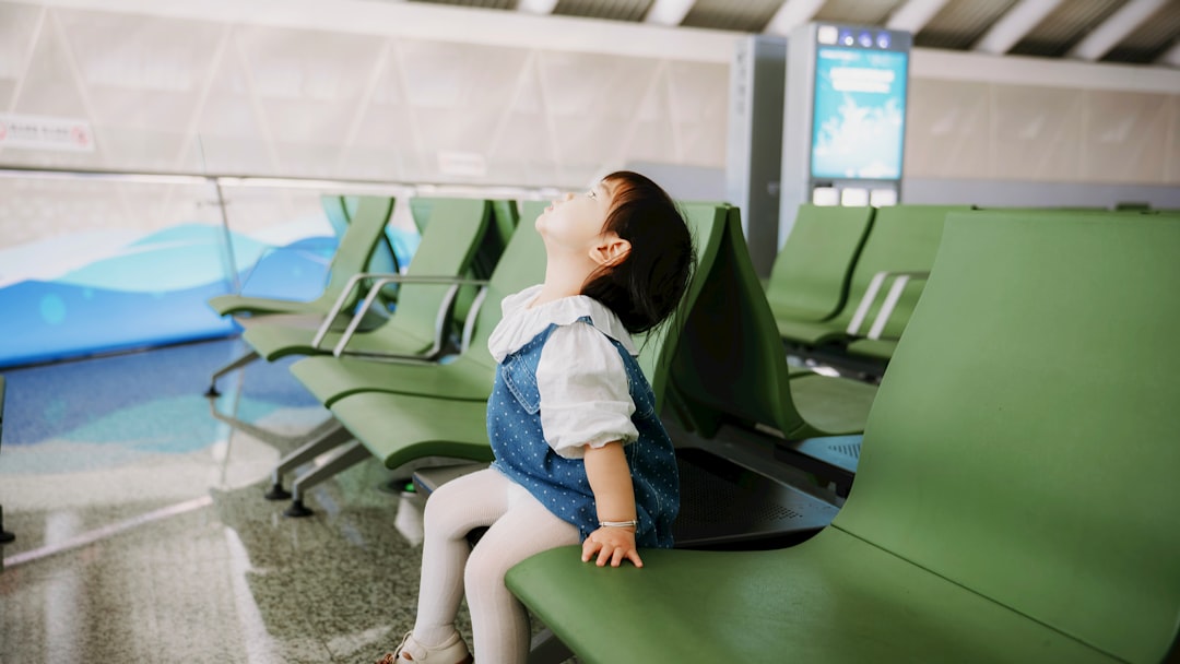 A young child sits on a green bench looking up.