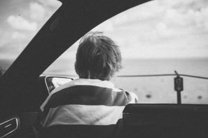 Child looks out car window at the ocean