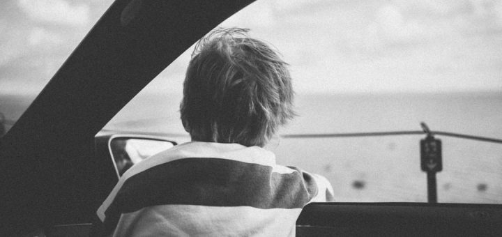 Child looks out car window at the ocean