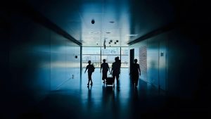 Silhouettes of people walking down a modern hallway.