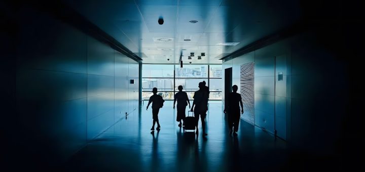 Silhouettes of people walking down a modern hallway.
