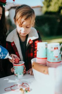 girl in red and white jacket holding blue and white ceramic mug